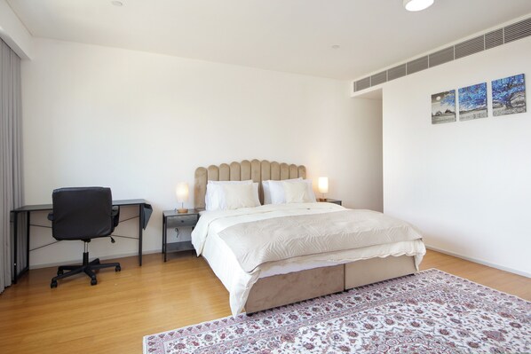 A bedroom with a bed, bedside tables, a desk, and a chair.