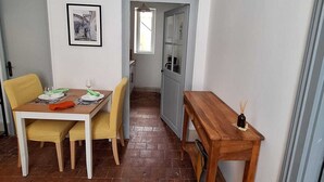 Un comedor con una mesa dispuesta para dos personas, una mesita auxiliar de madera y una silla.