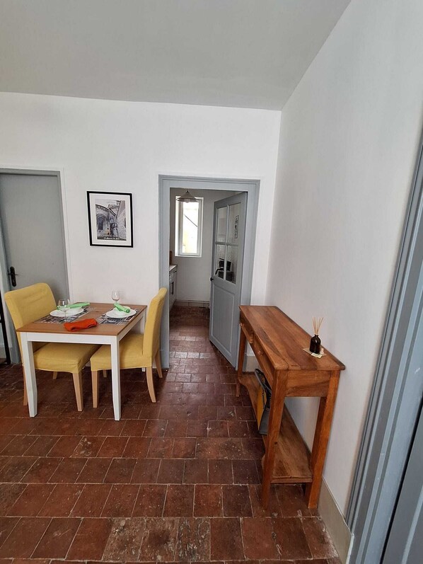 Un comedor con una mesa dispuesta para dos personas, una mesita auxiliar de madera y una silla.