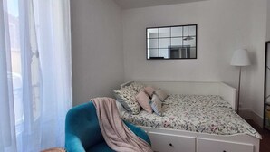 Un dormitorio con cama, una silla, un espejo y una lámpara.