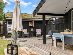 Eine Terrasse im Freien mit Holzterrasse, Gartenmöbeln und einem überdachten Sitzbereich.