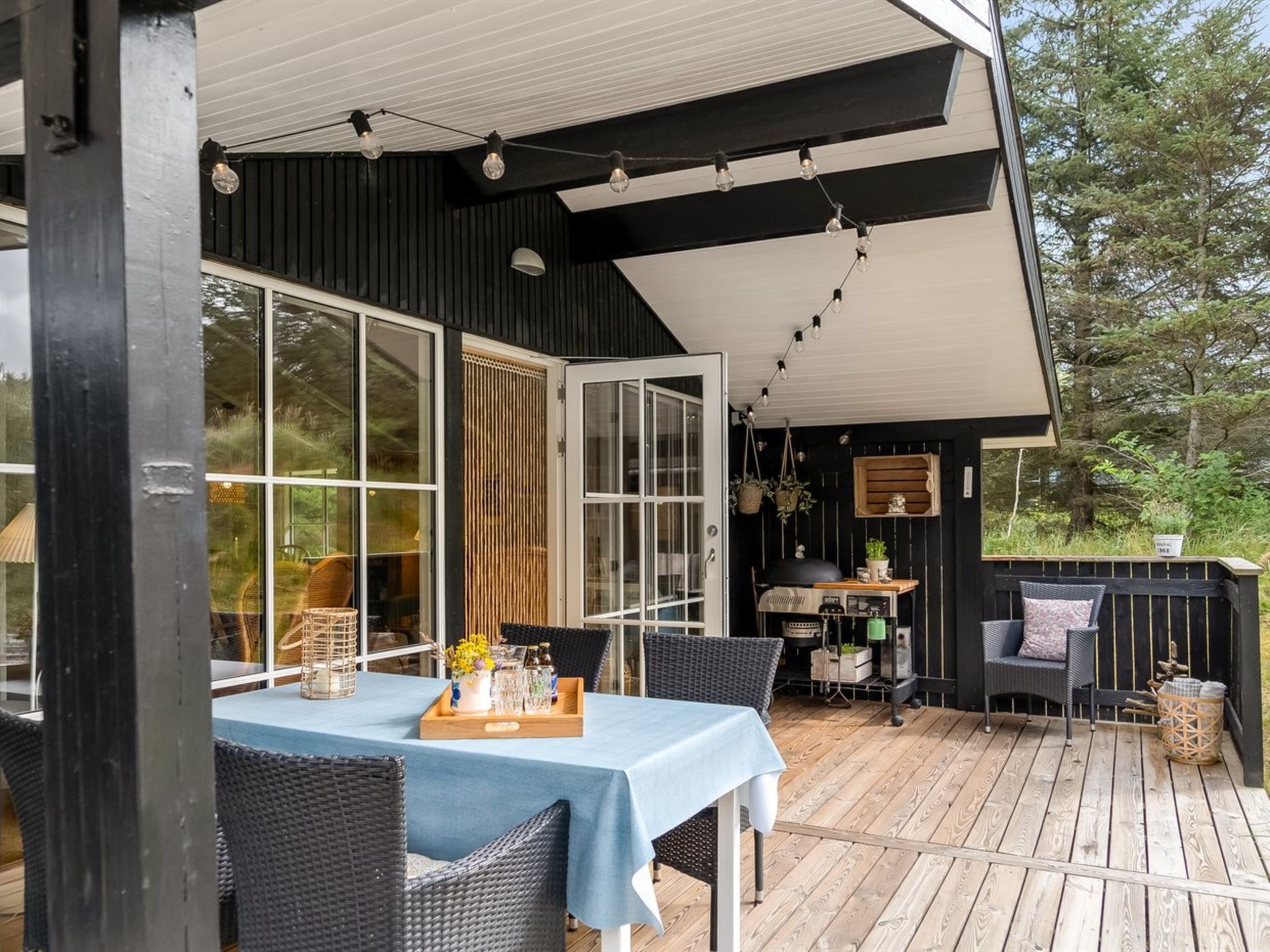 An outdoor patio with a table and chairs, a grill, and a wooden deck.