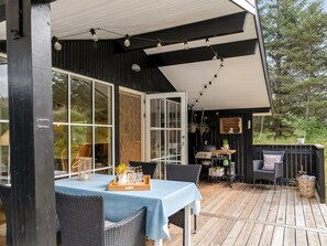 Eine Terrassenanlage im Freien mit Tisch, Stühlen, einem Grill und einem Holzdeck.