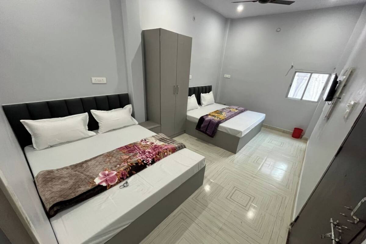 A modern bedroom with two beds, a wardrobe, and a small window.