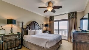 Une chambre d’hôtel avec un grand lit, un ventilateur de plafond, une télévision, un bureau et une vue sur l’extérieur.