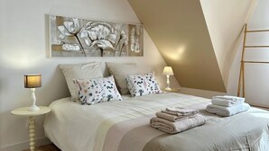 A modern bedroom with a large bed, a side table, a lamp, a painting, and a ladder. - Villa l'Escale with large garden (Daubeuf-Serville)