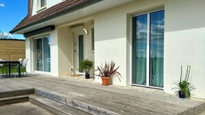 A modern house with a wooden deck, large sliding glass doors, and potted plants. - Villa l'Escale with large garden (Daubeuf-Serville)