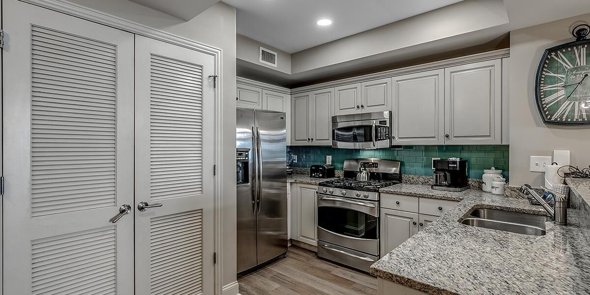 A modern kitchen with white cabinets, stainless steel appliances, and a granite countertop.