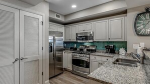 Una cocina moderna con armarios blancos, electrodomésticos de acero inoxidable y encimera de granito.