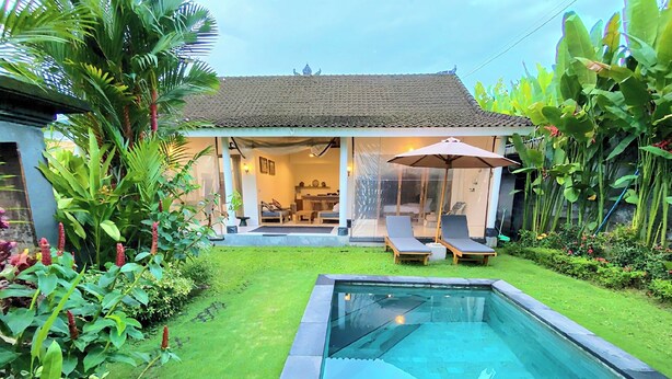Ein modernes Haus mit Swimmingpool, einer Terrasse mit Liegestühlen und üppiger Bepflanzung.