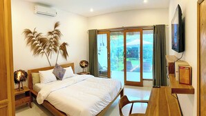 Ein Schlafzimmer mit einem Bett, einem Schreibtisch, einem Stuhl, einem Fernseher und einer Glasschiebetür, die auf einen Balkon führt.