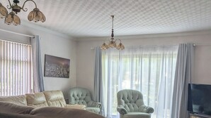 A spacious bedroom with a large bed, two armchairs, a television, and a patterned carpet.