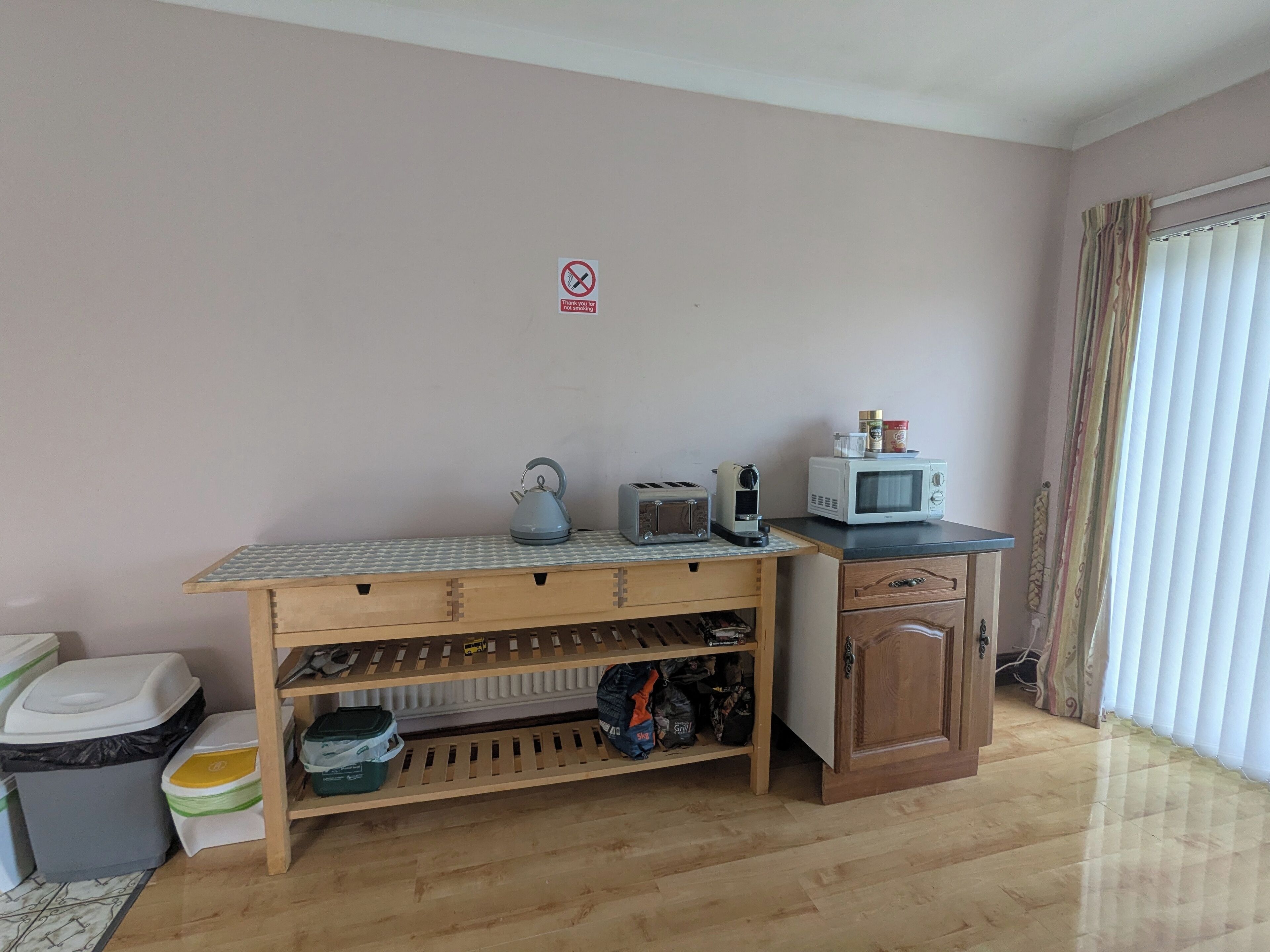 A kitchenette with a microwave, toaster, kettle, and storage shelves.