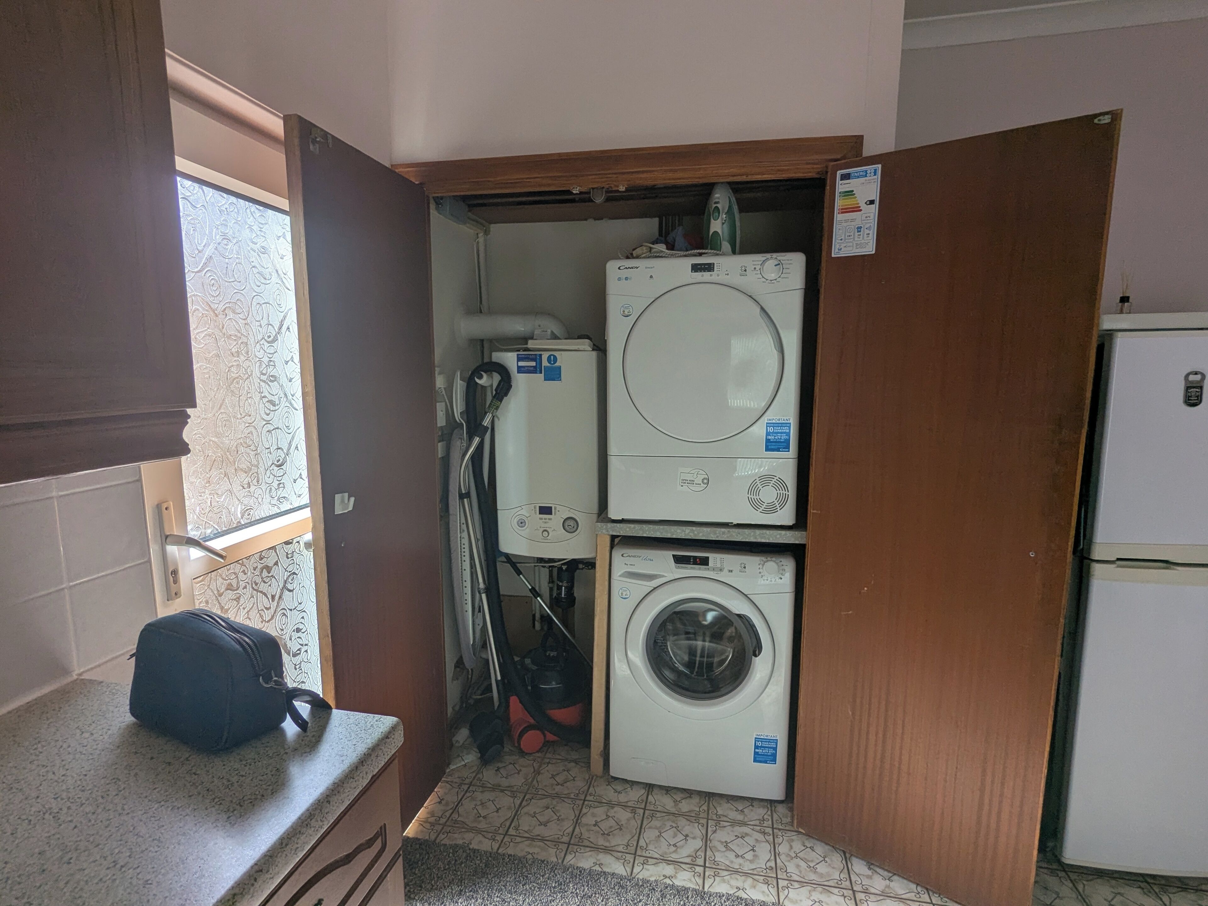 Ein kleiner Hauswirtschaftsraum mit Waschmaschine, Trockner und einem Kühlschrank.