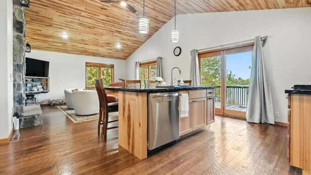 A spacious kitchen with wooden cabinets, a central island, and a dining area with a sofa and chairs. - Lunar Lodge on Windfall Lake (Exeland)