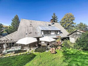 A large house with a stone facade, a metal roof, and a fenced backyard with outdoor furniture.