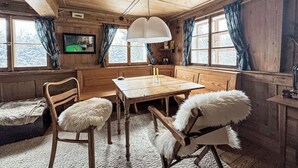 A cozy wooden cabin interior with a dining table, chairs, a sofa, and a television mounted on the wall. - Beautiful private villa for 6 guests with terrace (Altglashütten)