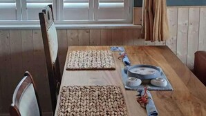 Una mesa de madera con individuales tejidos, una bandeja azul con un objeto blanco y un artículo enrollado sobre la mesa.