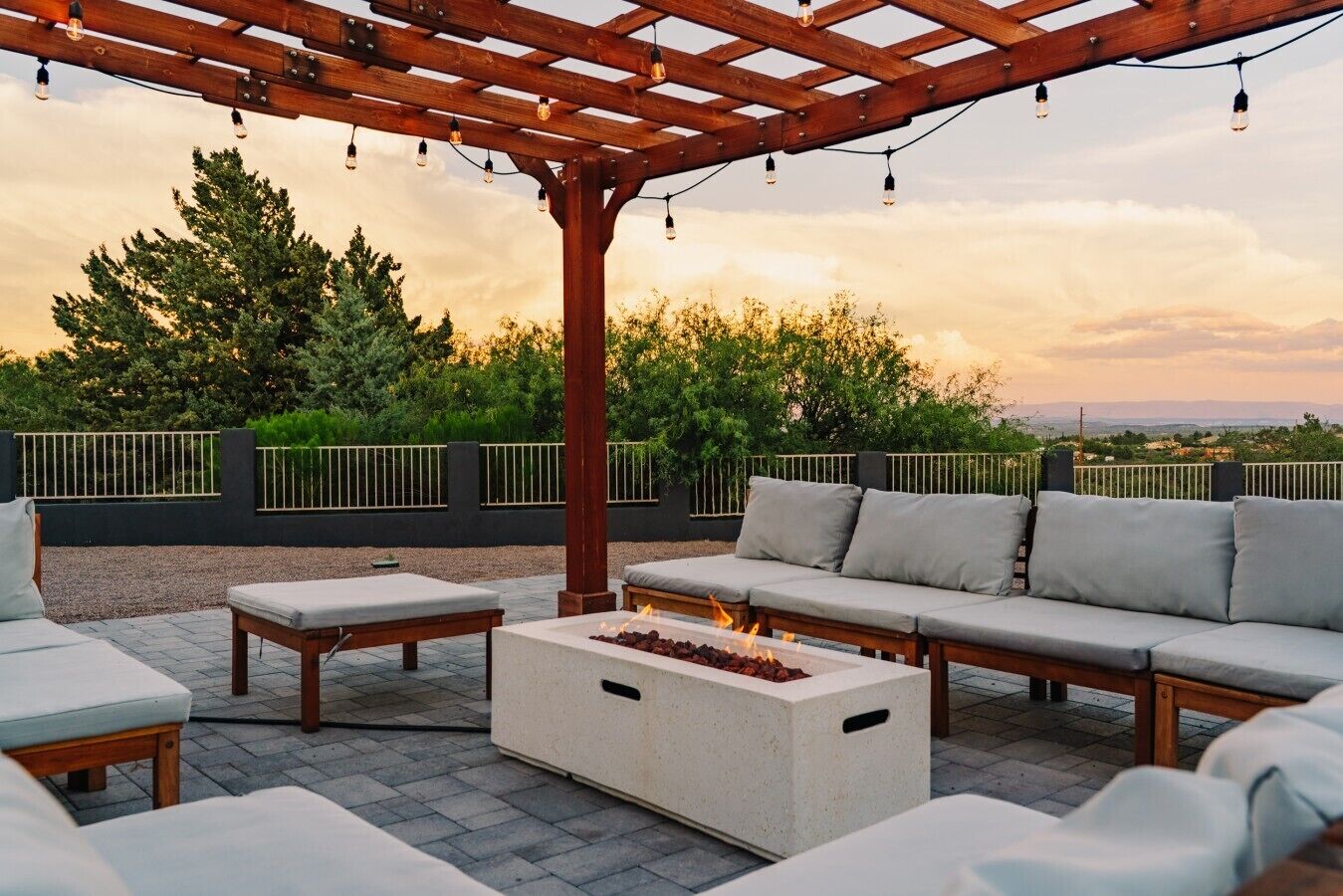 An outdoor seating area with a pergola, fire feature, and a view of the landscape.