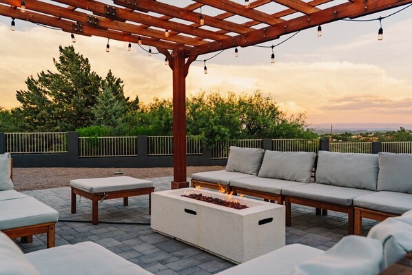 An outdoor seating area with a pergola, fire feature, and a view of the landscape.