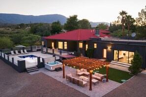 Una casa moderna con piscina, mobiliario de exterior y un patio cubierto.