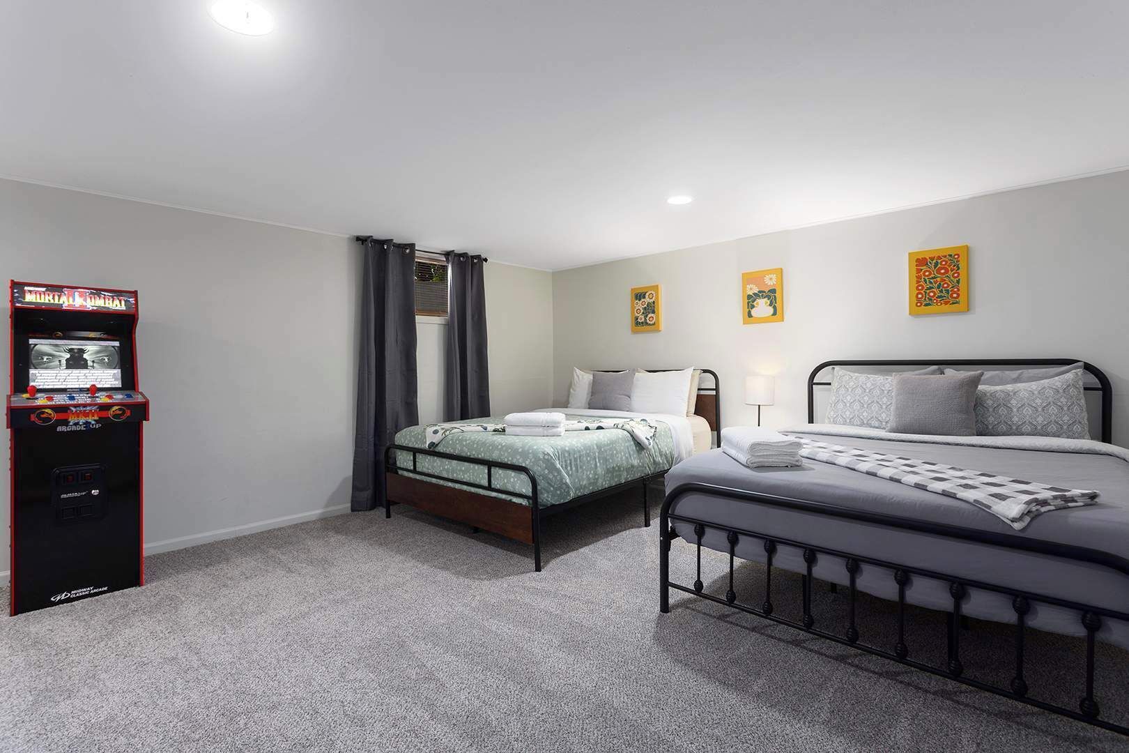 A bedroom with two beds, a small table, and a gaming console.