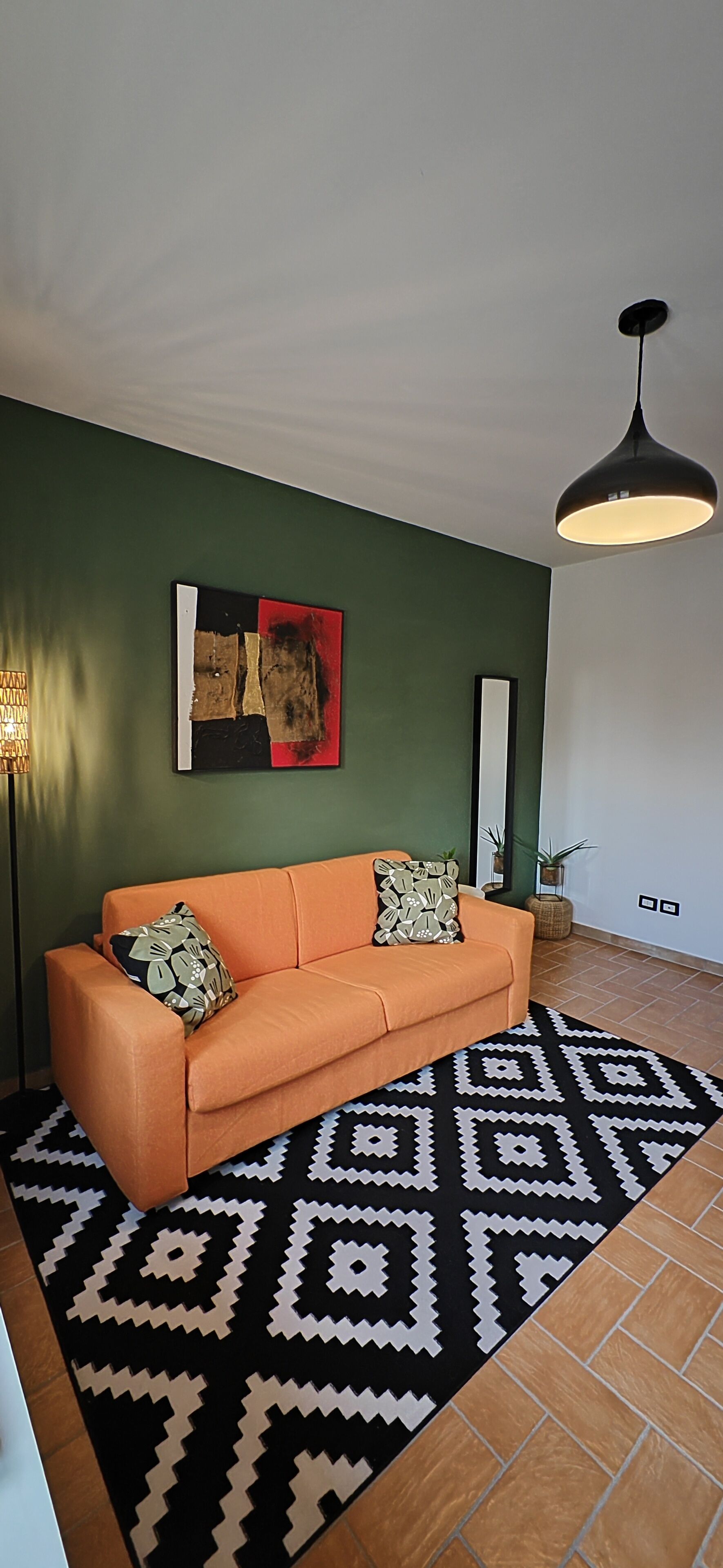 A living room with a sofa, patterned rug, and a painting on the wall.