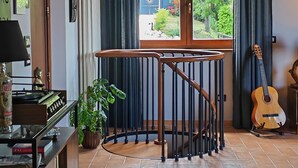 Una stanza con pavimento a spina di pesce, travi in legno a soffitto, una scala, una chitarra e vista sull'esterno.