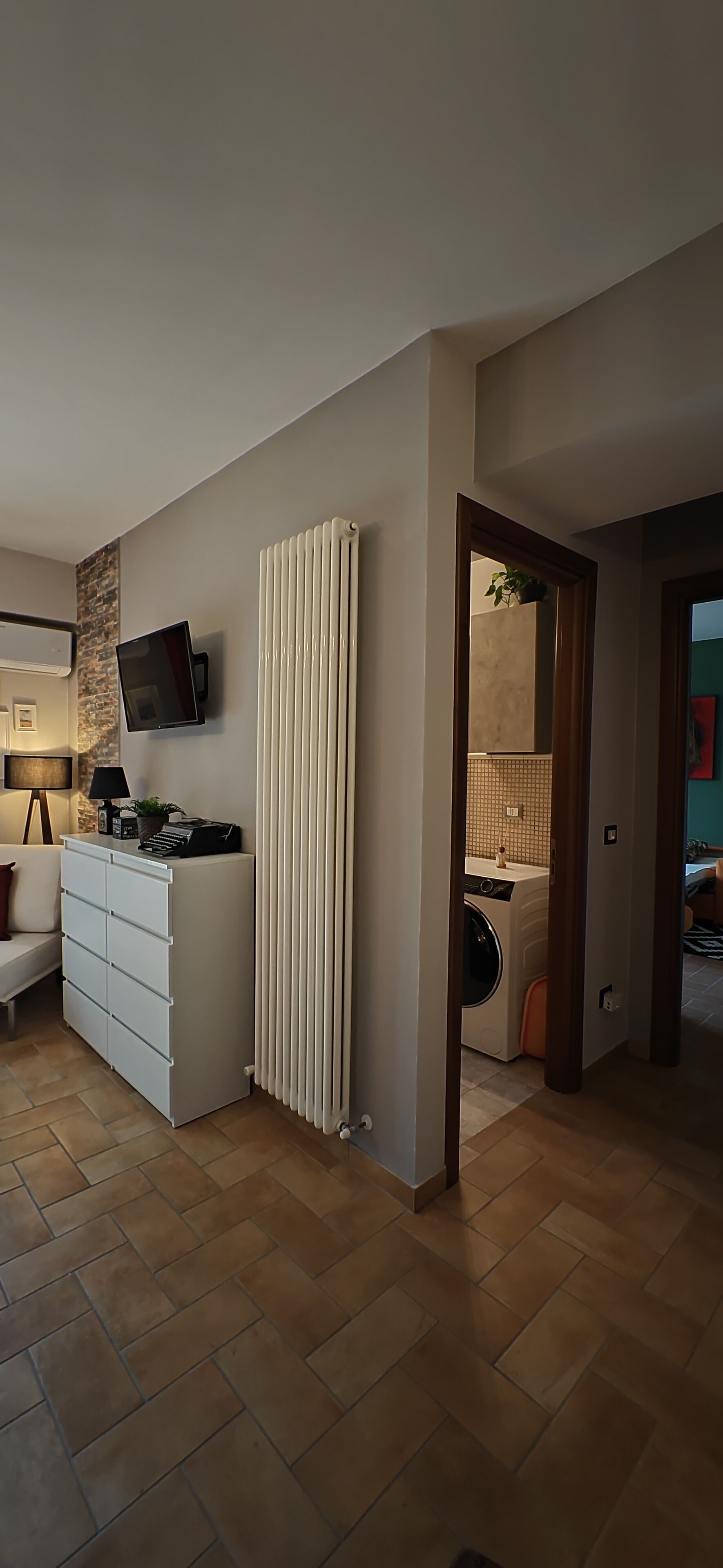 A modern living room with a white cabinet, a flat-screen TV, and a radiator.