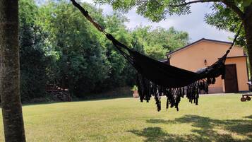 A hammock hanging between trees in a grassy area with a building in the background.
