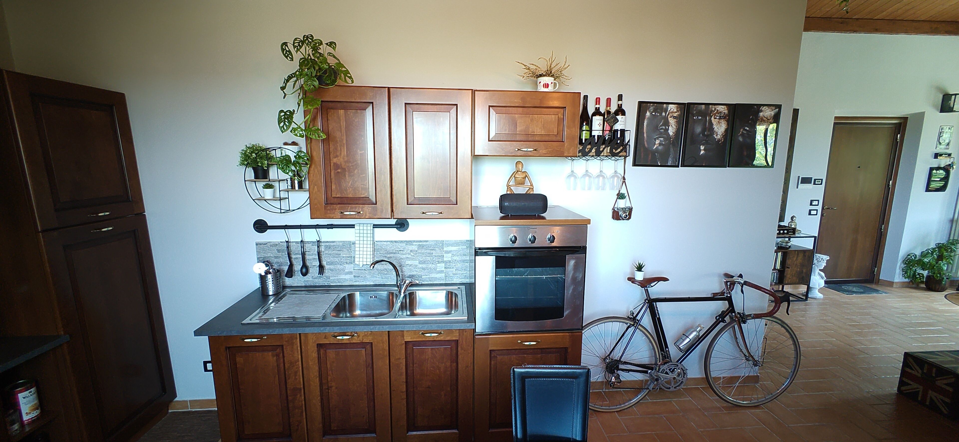 A kitchen with wooden cabinets, a stainless steel sink, an oven, and a bicycle.