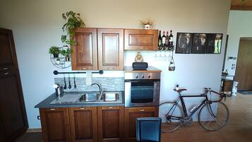 A kitchen with wooden cabinets, a stainless steel sink, an oven, and a bicycle.