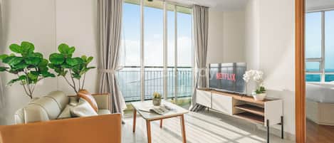 Un salon moderne avec un canapé, une table basse, un téléviseur et un balcon offrant une vue agréable.