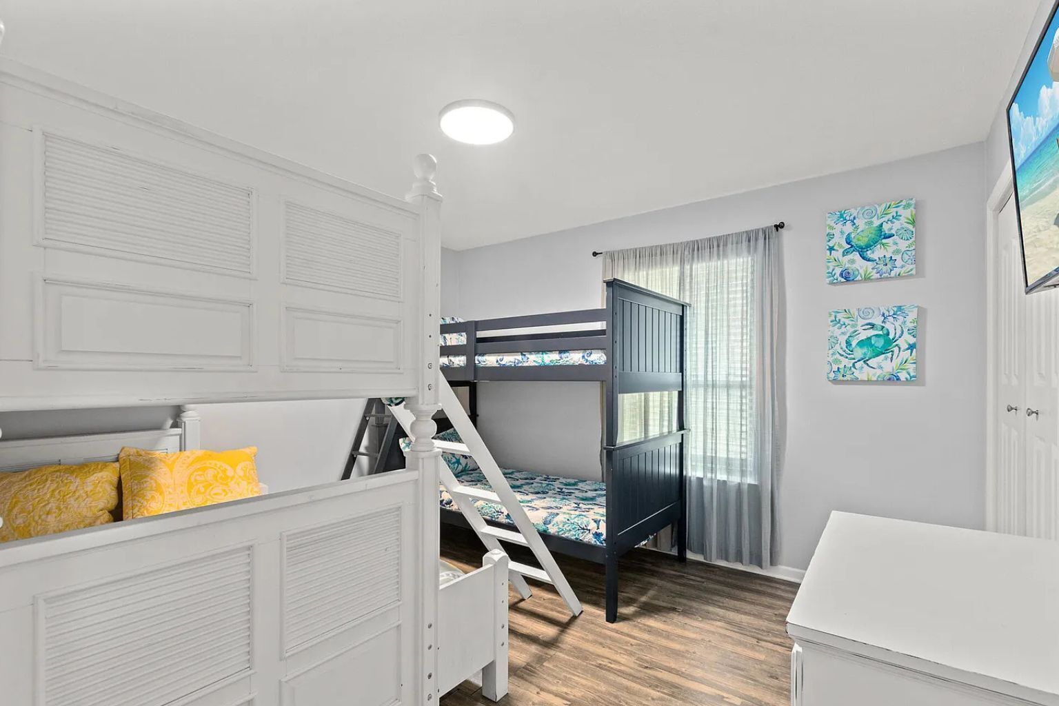 Ein Zimmer mit Etagenbetten, einer weißen Kommode und zwei gerahmten Bildern an der Wand.