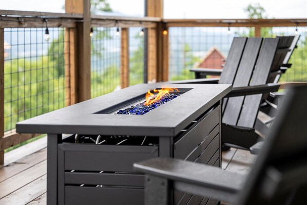 An outdoor patio with a built-in fire feature and wooden furniture.