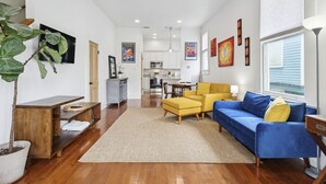 A modern living room with a sofa, ottoman, and a dining area in the background. - Fully Furnished 2bd/1.5ba One Block from Carrolton (New Orleans)