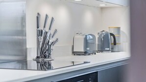 Eine moderne Küche mit Edelstahl-Kochgeschirr, einem Toaster und einem Wasserkocher auf einer weißen Arbeitsplatte.