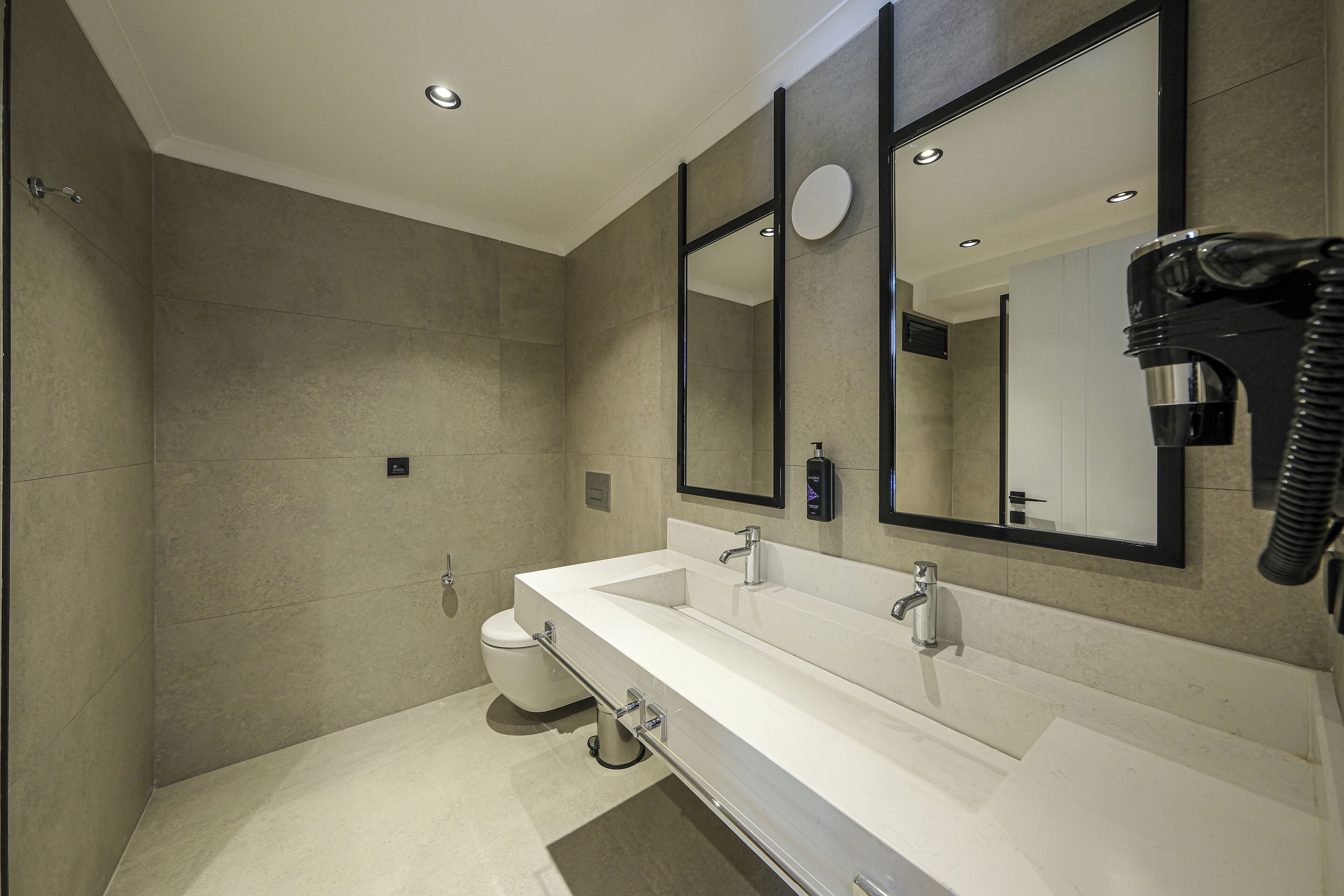 A modern bathroom with a large mirror, a sink, and a toilet.