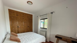 A bedroom with a large wooden wardrobe, a single bed with pillows, a window with curtains, and a radiator. - Spanish country house. Completely free, yet two restaurants within walking distance. (COMARES)