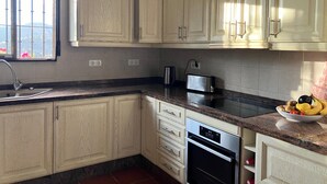 A kitchen with light wooden cabinets, a stainless steel toaster, a built-in oven, and a window with a view of greenery. - Spanish country house. Completely free, yet two restaurants within walking distance. (COMARES)