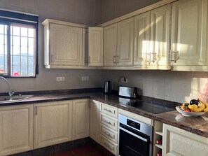A kitchen with light wooden cabinets, a stainless steel toaster, a built-in oven, and a window with a view of greenery. - Spanish country house. Completely free, yet two restaurants within walking distance. (COMARES)