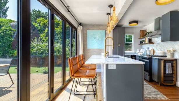 A modern kitchen with a large island, bar stools, and a view of the outdoors. - Division House Extended Stay (Walla Walla)