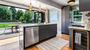 A modern kitchen with a large island, dark cabinetry, stainless steel appliances, and pendant lighting. - Division House Extended Stay (Walla Walla)