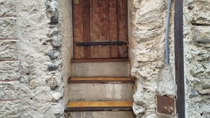 Paredede pedra com porta de madeira e degraus que a levam.