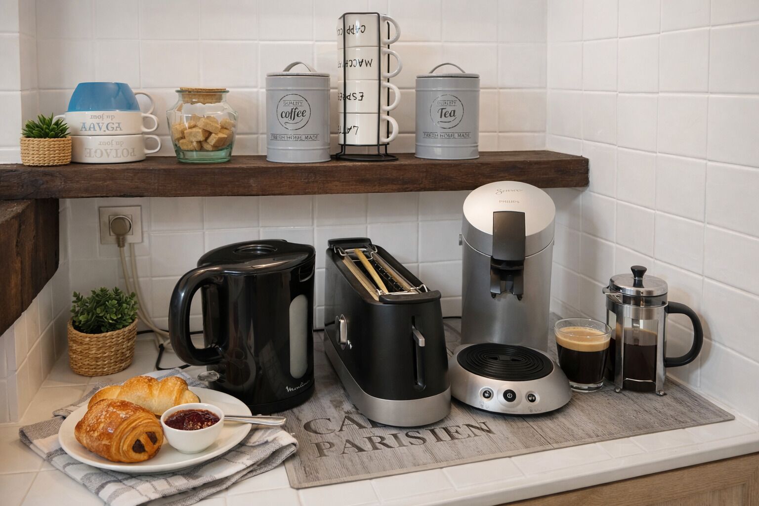 A kitchen with a coffee maker, toaster, and a coffee pot on the counter.