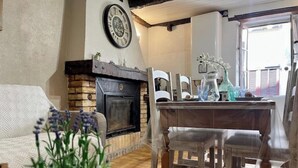 Uma sala de estar aconchegante com lareira, um espaço de jantar com mesa e cadeiras, e uma janela grande que traz luz natural.