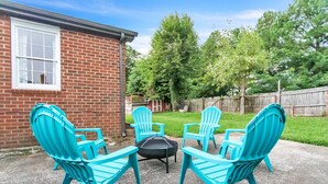 Un patio con cuatro sillas Adirondack turquesa dispuestas alrededor de un brasero negro.