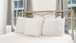 Una cama con cabecera de madera, ropa de cama blanca y dos almohadas.
