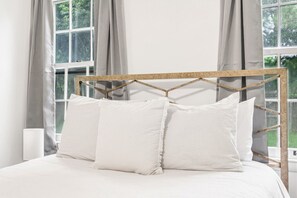Ein Bett mit einem hölzernen Kopfteil, weißer Bettwäsche und zwei Kissen.