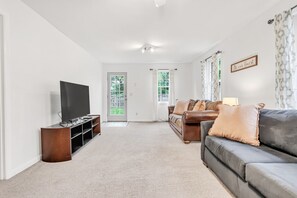 A living room with a flat-screen TV, leather sofas, and a door leading outside.